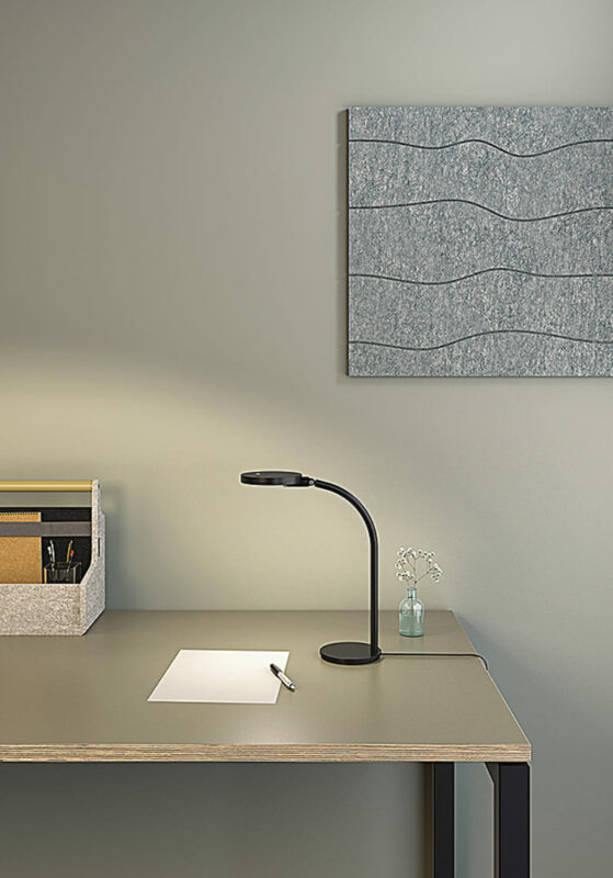 Lampe de bureau Loola Mini posée sur un bureau moderne, avec un éclairage doux et un décor minimaliste en arrière-plan.