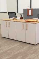 Comptoir Tandem blanc avec plateau en bois clair et poignées dorées, doté d’un design épuré et idéal pour les bureaux partagés ou zones d’accueil.