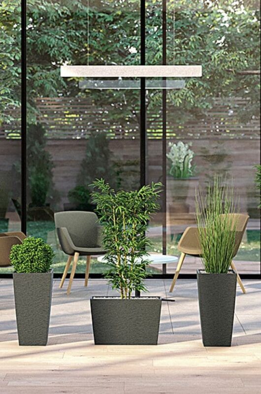 Une collection de bacs à plantes Columbia en différentes tailles, intégrés dans un espace lumineux, avec une vue sur un jardin verdoyant.