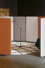 Espace acoustique créé avec des cloisons Taoma en cercle, intégrant un microphone sur un tapis géométrique pour un studio moderne.