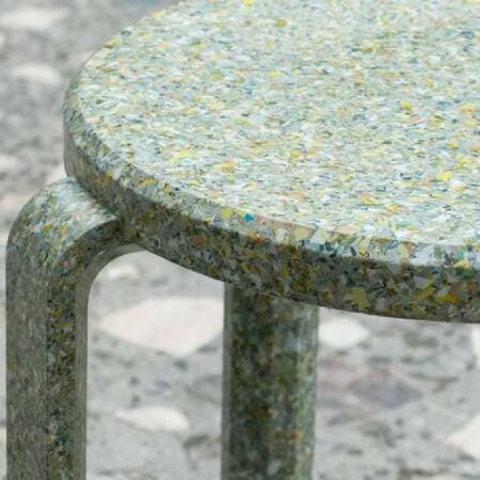 Gros plan sur le plateau du tabouret Billex, mettant en évidence sa texture unique composée de fragments de billets recyclés.